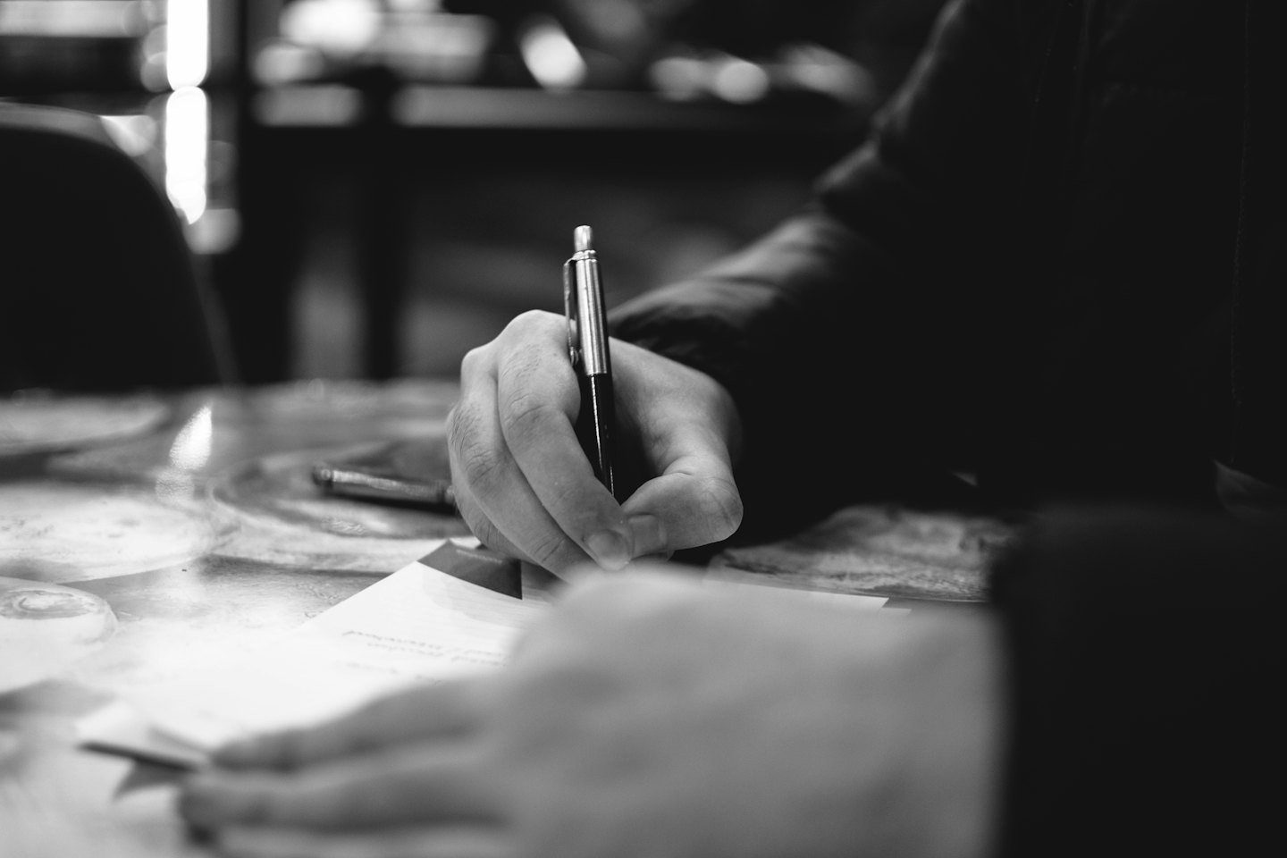 Händer som skriver med en penna på ett dokument.